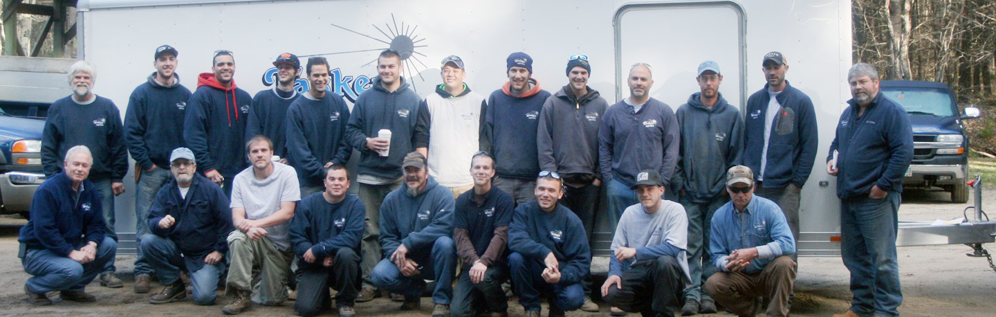 Tasker Landscaping’s team standing and kneeling together beside company trucks